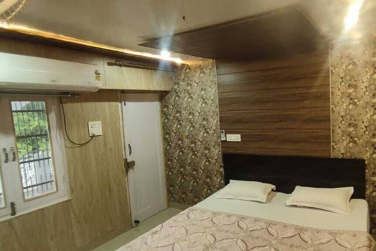 A bedroom with a bed, wooden paneling, and a window with bars.