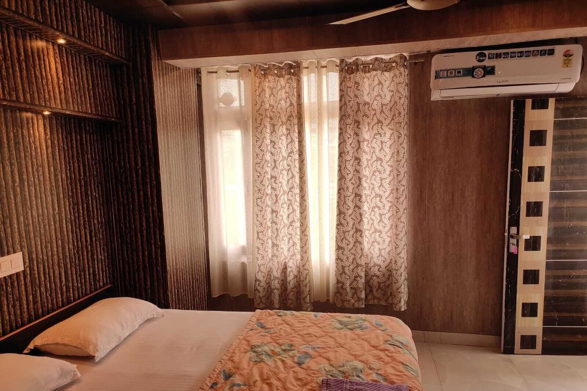 A hotel room with a bed, curtains, a wooden wall, and a ceiling fan.