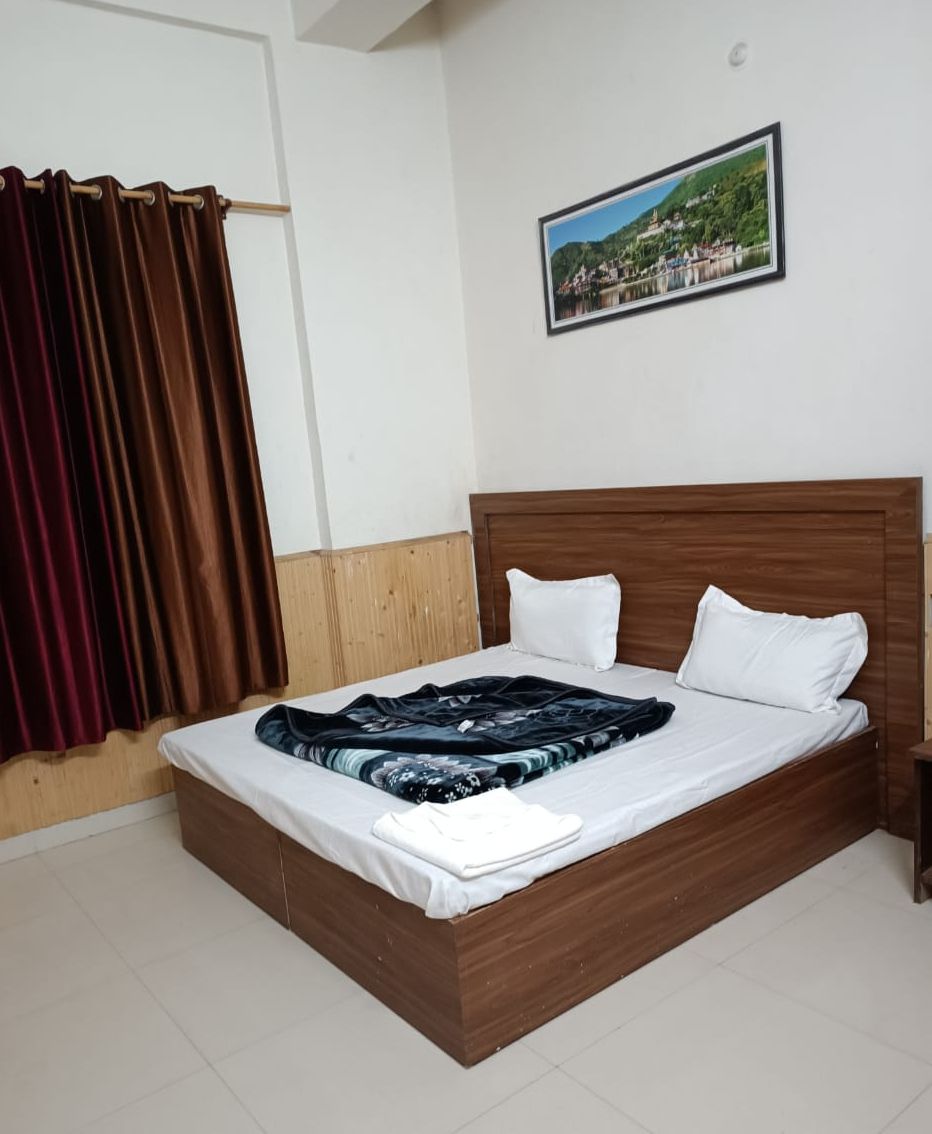 Una cama bien hecha con cabecera de madera, almohadas blancas y una colcha azul y blanca.
