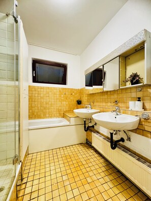 Une salle de bain avec deux lavabos, une baignoire et une douche.