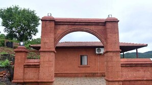 A brick structure with an archway, a small window, and an air conditioning unit. - Waves and Vibes Resort (Pune)