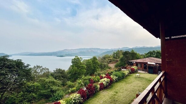 A balcony with a view of a lake and mountains. - Waves and Vibes Resort (Pune)