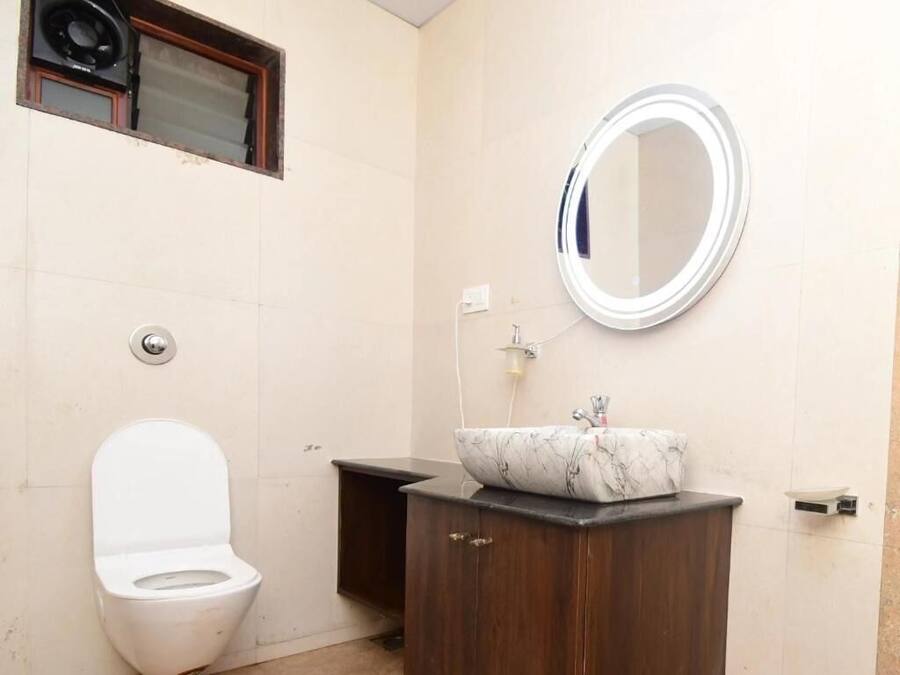 A bathroom with a white toilet, a marble sink, and a round mirror.