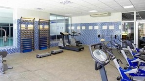 Een sportschool met loopbanden, een stairmaster en een wandrek.