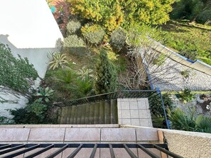 A staircase leading to a residential area with a garden and trees.