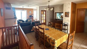A dining area with a wooden table and chairs, a sofa, and a television. - Family home in Port-Vendres with stunning view for 6 people (Port-Vendres)