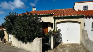 A residential building with a red-tiled roof, a white garage door, and a green awning. - Family home in Port-Vendres with stunning view for 6 people (Port-Vendres)