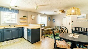 A modern kitchen with dark blue cabinets, a wooden island, and a dining area with a round table and chairs. - Blue Wave Retreat in Heart of Myrtle Beach (Myrtle Beach)