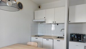 A compact kitchen with white cabinets, a wooden table, and a built-in microwave.