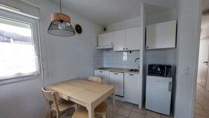 A compact kitchen with white cabinets, a wooden table, and chairs.