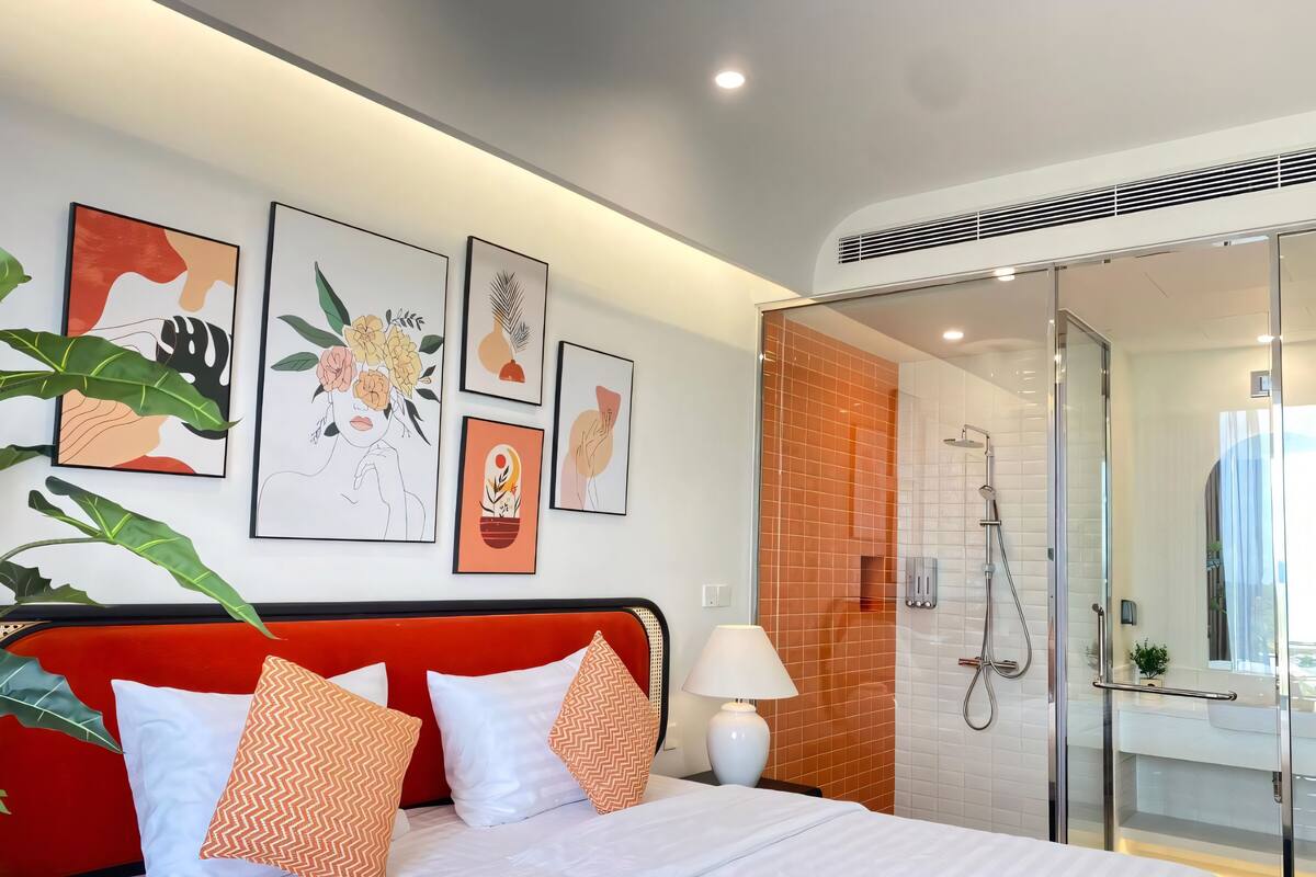 Une chambre d’hôtel moderne, équipée d’un lit, d’une douche et ornée d’œuvres d’art au mur.