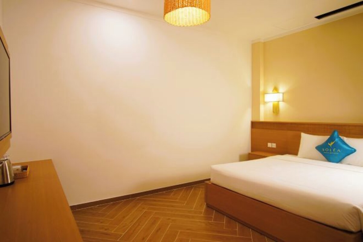 Une chambre d’hôtel avec un lit, une table de chevet avec une lampe et un plancher en bois.