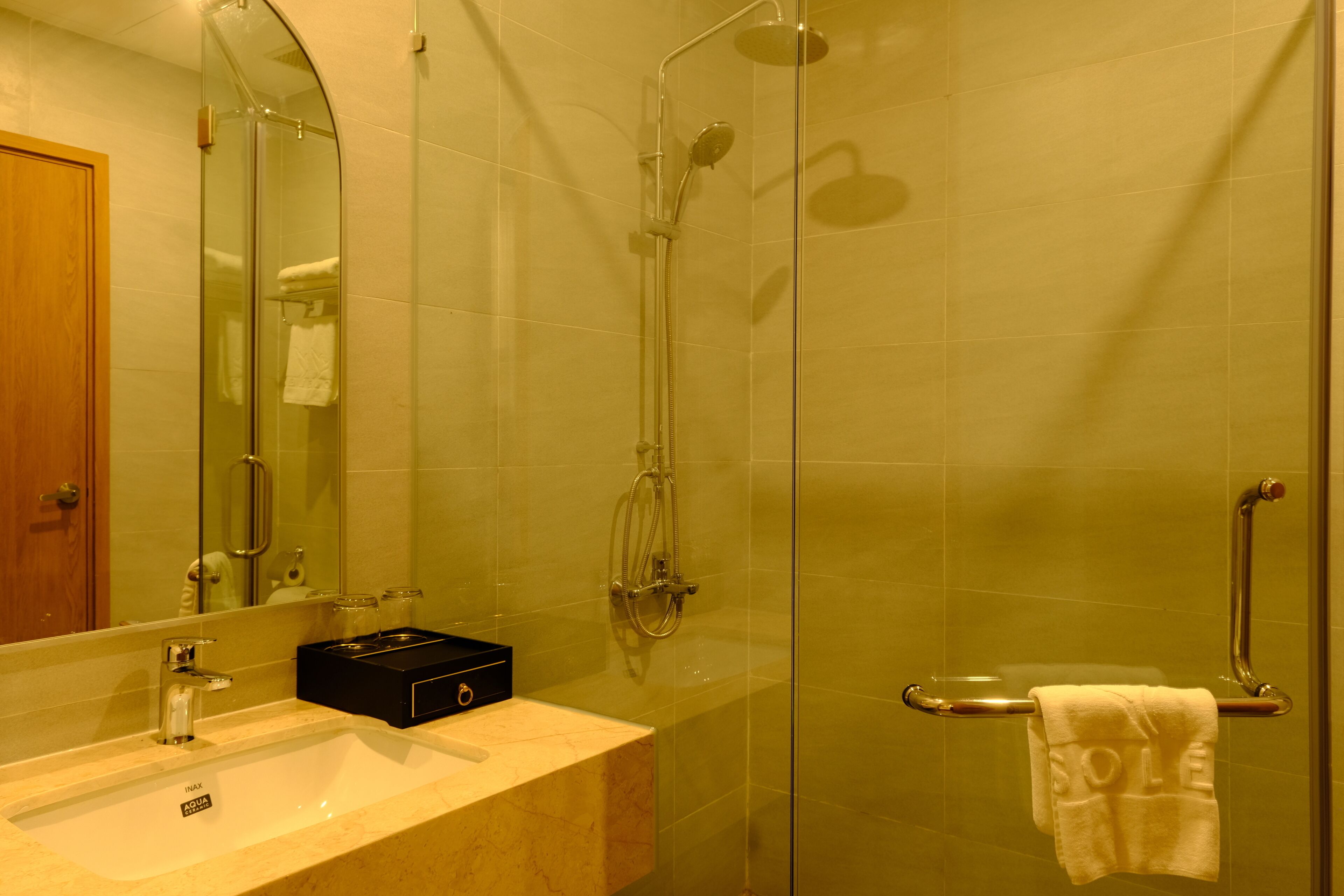 Une salle de bain avec une douche à parois de verre, un lavabo avec un miroir et un porte-serviettes.