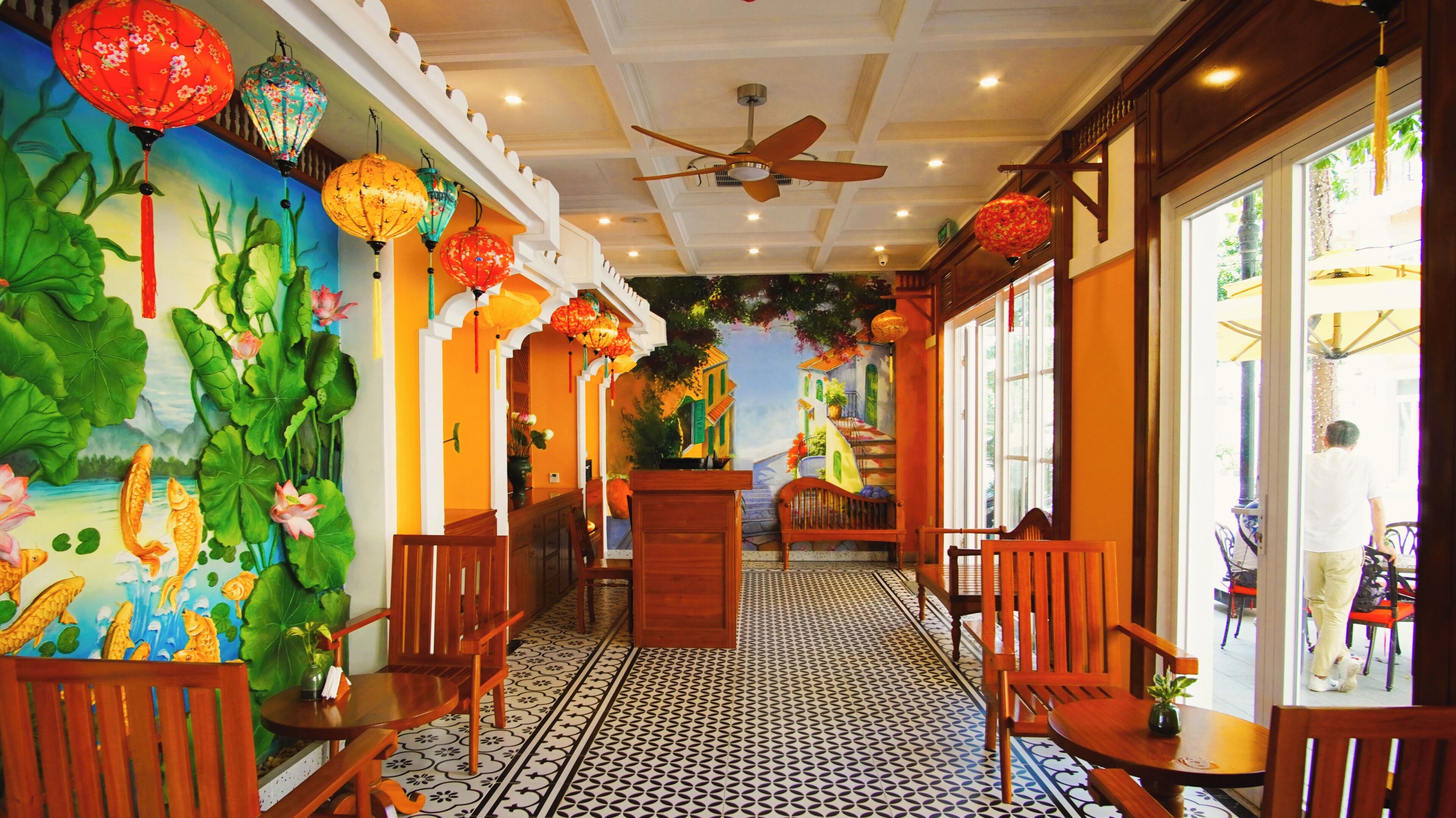 A hallway with a tiled floor, wooden chairs, a wooden bench, and a ceiling fan.