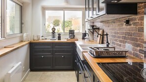 A modern kitchen with a skylight, dark cabinets, and a brick accent wall.