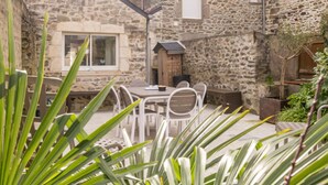 A stone building with a patio area featuring a table and chairs.