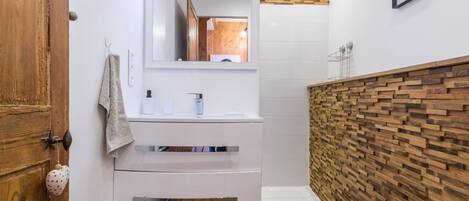 A modern bathroom with a wooden vanity, a white sink, and a wooden wall panel.