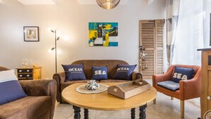A living room with a brown sofa, two armchairs, a wooden coffee table, and a painting on the wall.