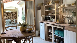 Una cocina compacta con comedor, que incluye una mesa de madera, sillas, un refrigerador pequeño y un microondas.