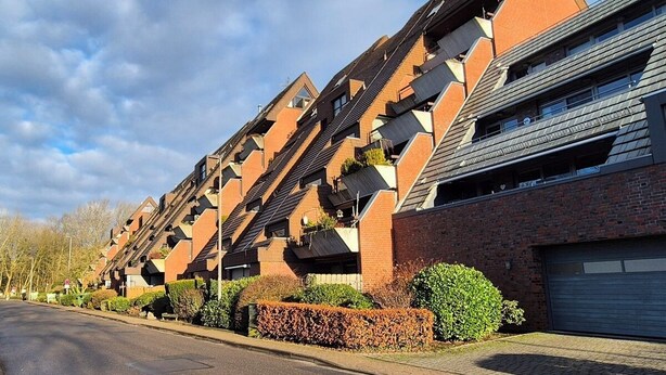 A row of modern apartment buildings with a unique angular design, featuring multiple balconies and a brick facade. - 5 DTV star vacation apartment on Lake Stella with marina view (Bad Zwischenahn)
