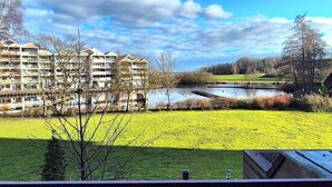 A residential area with a large building complex, a pond, and a grassy field. - 5 DTV star vacation apartment on Lake Stella with marina view (Bad Zwischenahn)