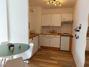 Compact kitchen with dishwasher, microwave, and wooden countertop.
