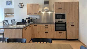 A modern kitchen with wooden cabinets, stainless steel appliances, and a dining area with a table and chairs.