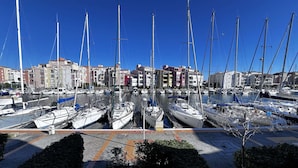 A marina with multiple sailboats docked, surrounded by multi-story buildings. - Quiet Studio Cabin, Canal View, Near Beach and Shops (Cap d'Agde)