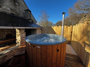 Ein hölzernes Whirlpool-Becken im Hinterhof, umgeben von Steinmauern und einer Holzterrasse.