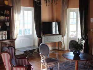 Ein Wohnzimmer mit Fernseher, Bücherregal, Esstisch und einer Katze.