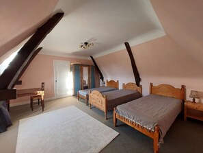 Ein Schlafzimmer mit zwei Holzbetten, einem weißen Teppich, einem Holzstuhl und einem kleinen Tisch mit einer Lampe.