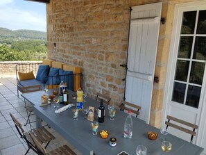 An outdoor dining area with a stone wall, a table set with various items, and a view of the countryside. - Charming 6-bedroom house in Dordogne for a peaceful getaway (Sainte-Mondane)