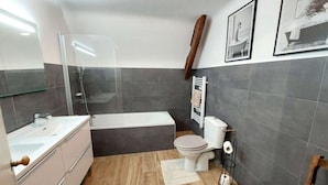 Un baño moderno con bañera, inodoro y tocador.
