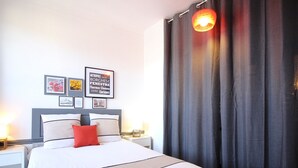 A neatly made bed with a white and red pillow, a grey headboard, and a framed quote on the wall. - Central La Bourboule T2 Apartment, 4 pers, Wifi (La Bourboule)