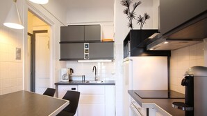 A compact kitchen with white cabinets, a coffee machine, a sink, and a stove. - Central La Bourboule T2 Apartment, 4 pers, Wifi (La Bourboule)