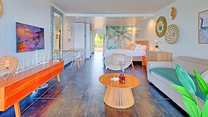 A modern living room with a dining area, a bed with a view, and a large mirror.