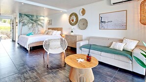 A modern bedroom with a bed, a sofa, a round wooden table, and a large window.