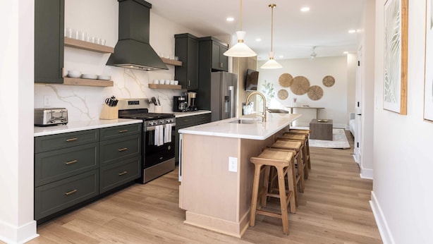 A modern kitchen with dark cabinets, a central island, wooden stools, and a large island sink. - New Build-Rooftop-Steps from the Beach! Unit Salt (Virginia Beach)