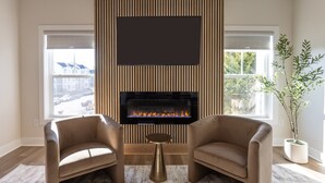 A modern living room with a fireplace, two leather sofas, and a large window. - New Build-Rooftop-Steps from the Beach! Unit Salt (Virginia Beach)