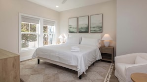 A bedroom with a bed, bedside tables, a ceiling fan, and artwork on the wall. - New Build-Rooftop-Steps from the Beach! Unit Salt (Virginia Beach)