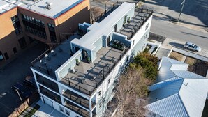 A multi-story building with a rooftop deck, a covered outdoor area, and a parking lot.