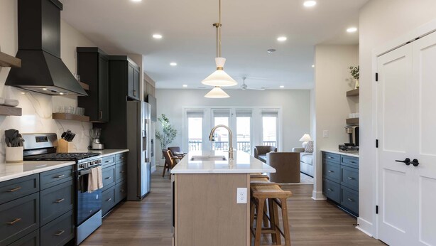 A modern kitchen with dark cabinetry, a central island, and a pendant light.