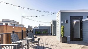 A rooftop deck with Adirondack chairs, a small table, and a potted plant.