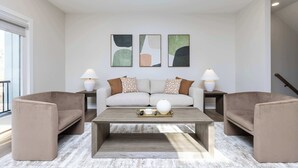 A modern living room with a sofa, two armchairs, a coffee table, and wall art.