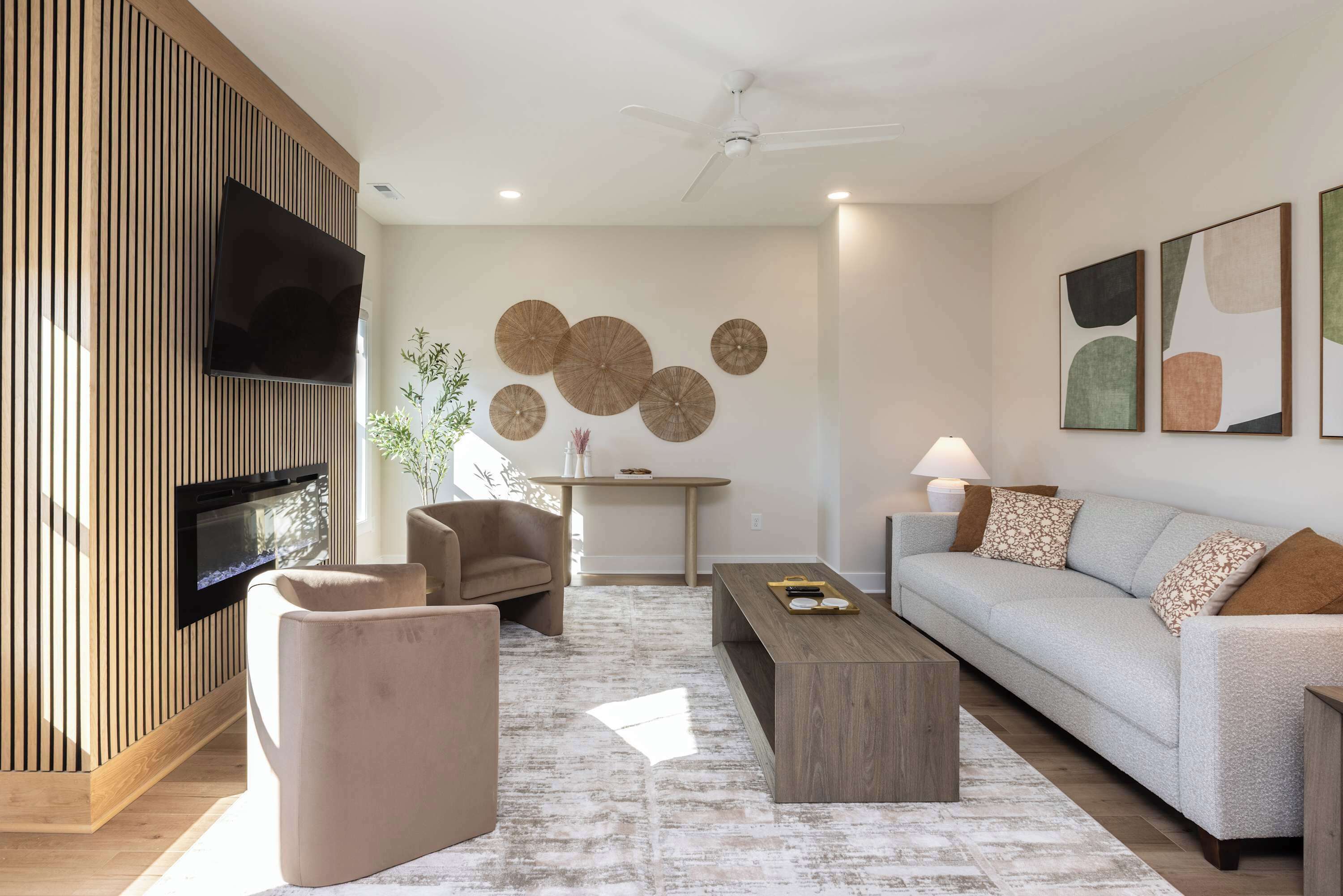 A modern living room with a flat-screen TV, a sofa, a coffee table, and a fireplace.