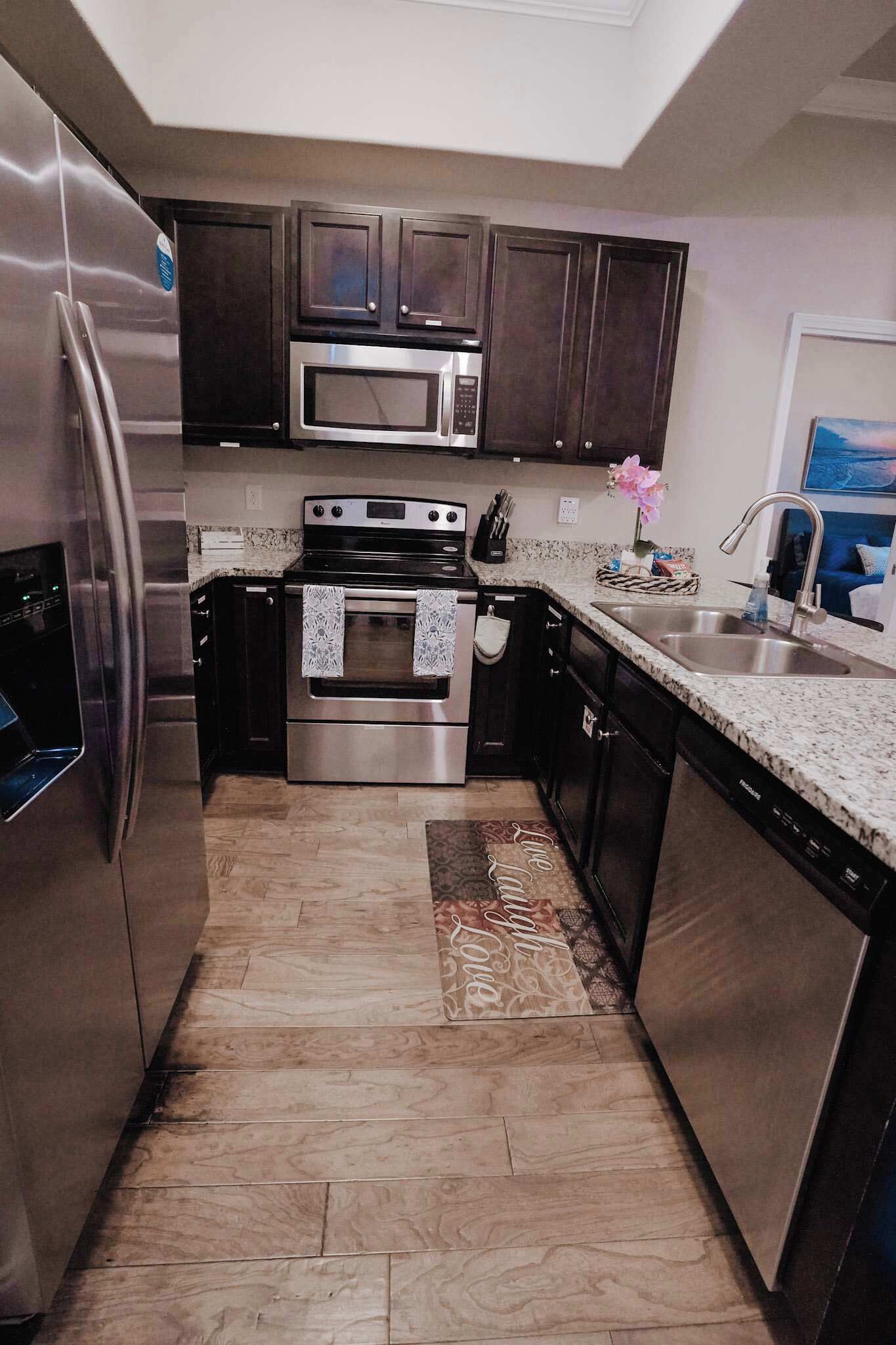 A modern kitchen with stainless steel appliances, dark cabinets, and a granite countertop.