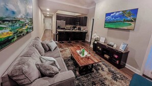 A living room with a sofa, coffee table, and artwork on the walls. - Beachside Bliss-Minutes from Beach, Pool, Hot Tub, Near Golf (Miramar Beach)