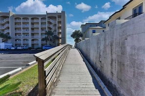Une promenade en bois menant à un immeuble à plusieurs étages doté de balcons.