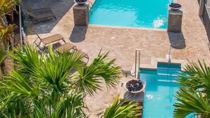 A rectangular swimming pool with a tiled deck, surrounded by lounge chairs and a covered seating area. - Beachside Bliss-Minutes from Beach, Pool, Hot Tub, Near Golf (Miramar Beach)