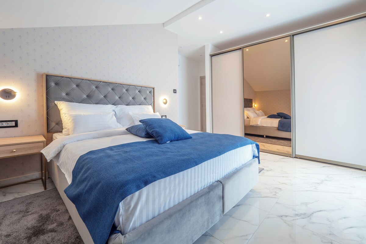 A modern bedroom with a bed, nightstands, and a large mirror.